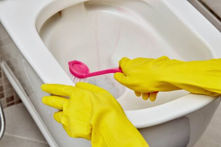 Wash the toilet and clean with a small pink brush. Daily routine. Household duties.の写真素材
