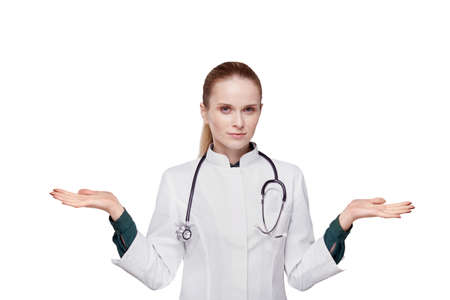 The concept of choosing a medicine, treatment. A young girl is looking at the camera. Young woman holding hands to the sides. Isolated white background.の写真素材