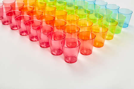 Red, orange, yellow, green, blue. Multi-colored glasses of glass standing in a row on a white background. Recycled material. Caring for the environment.の写真素材