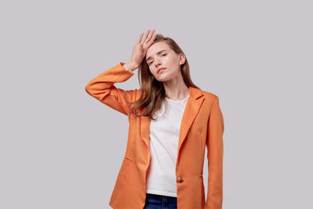 Very tired from work and household chores, a young beautiful girl. Human emotions. Gray background.の写真素材