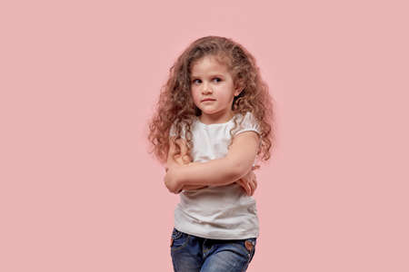 Beautiful girl with curly hair folded her hands together and looks away. Pink background.の写真素材