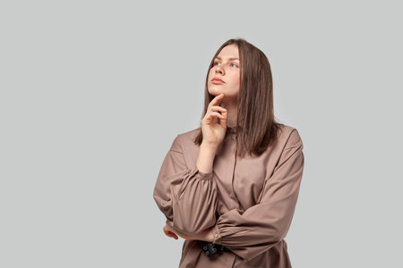 Beautiful woman with a pensive face looks away. Gray background.