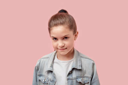 Close up portrait of a beautiful girl in a fashionable denim jacket. Brown eyes. Looks at the camera. Pink background.の写真素材
