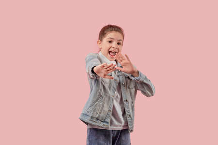 A frightened beautiful girl put her hands forward. The child is protected from violence. Pink background.の写真素材