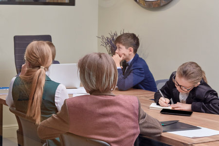 Young businessmen at a board meeting in the office. Working office. Children are businessmen.