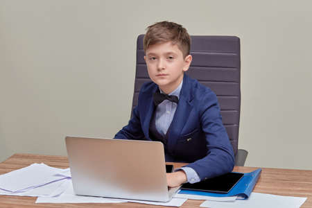 Portrait of a young businessman sitting at a conference table. Children are businessmen. Business, formal suit.の写真素材