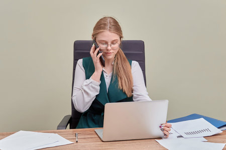 A blonde girl is sitting in the directors chair and talking on a cell phone. The working process. Office worker.の写真素材