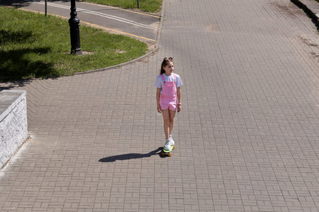 An overhead view of a cute brunette girl who is skating and enjoying the good weather. Hot summer...