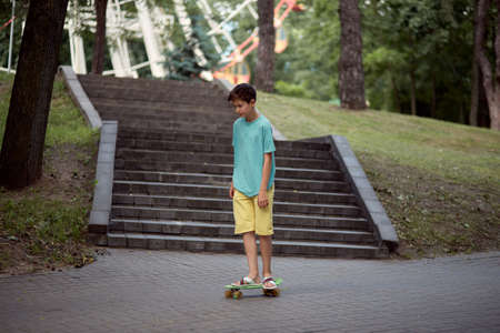 A teenage guy is riding a skateboard in the amusement park on a hot summer day. Summer walks. Blurred background.の写真素材