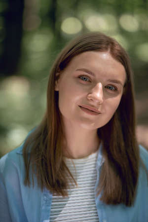 Vertical photo. Portrait of a young beautiful girl with clean skin. Looks into the camera. Summer...