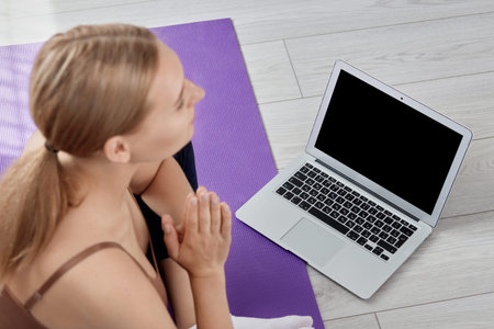 The girl is preparing for a yoga class. Focus on the laptop. The girl is blurred.