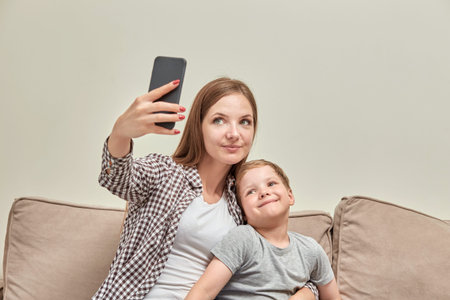 Young beautiful mother sitting with her son makes a photo for memory. A happy family.