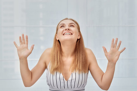 Happy young blonde woman rejoices and looks up. Portrait of a beautiful girl.