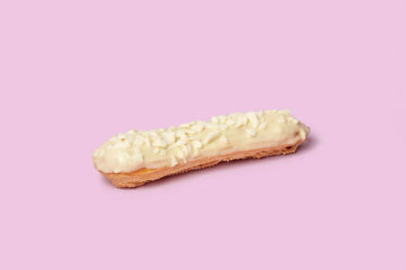 A mouthwatering Eclair filled with white chocolate and bits of coconut. White milk chocolate. Isolated on a pink background.の写真素材