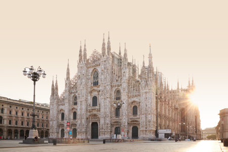 The golden sunshine is reflecting on the front of the magnificent Duomo di Milano or Milan...
