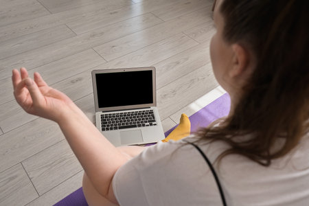 View from the back of a young woman who plays sports and looks at the laptop screen. Sports during...