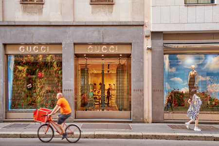 Showcase of a fashion store clothing GUCCI. The front door of the store. A man is riding a bicycle...