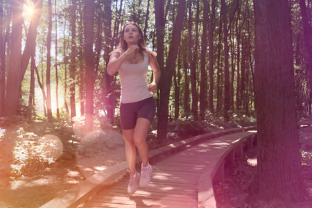 Beautiful young athletic woman running in the woods on a bright Sunny day. Healthy lifestyle.