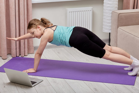 Sports activities at home online with the help of a training lesson. Sports lifestyle. The laptop is...