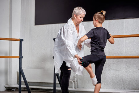 A beautiful young woman teacher teaches a young man ballet. Ballet school.