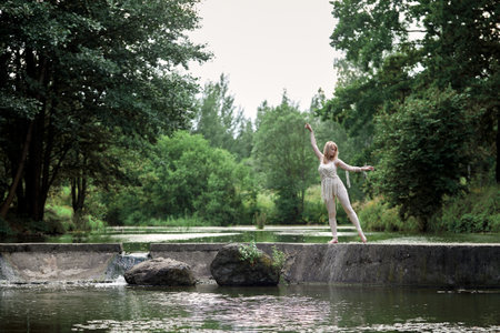 Beautiful young slender blonde girl dancing in nature. Clothing made of eco material. Hand made macrame.の写真素材