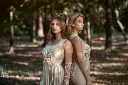 Two beautiful young women stand with their backs to each other. Women in love. The concept of natural cosmetics and harmony with nature. My hair is blowing in the wind. The concept of LGBT.の写真素材