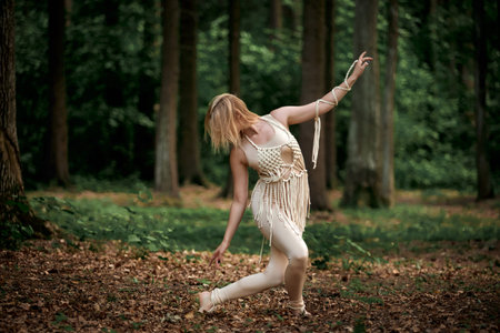 A woman dances in the forest in summer in beige clothes and macrame. Clothing of their eco-materials and macrame. The concept of natural products and harmony with nature.の写真素材