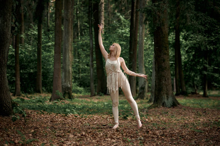 Blonde barefoot dancing in a dense forest in summer. Clothing of their eco-materials, macrame. The concept of natural products.の写真素材