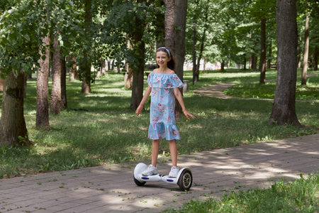 A girl in a blue dress rides through the Park on a gyro scooter. Long beautiful hair. Outdoor...
