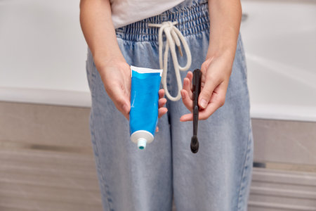 Womens hands holding a toothbrush and toothpaste. Care of the oral cavity.の写真素材
