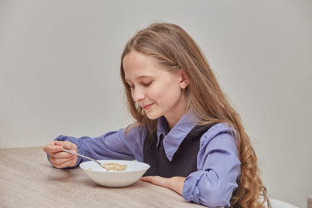 Beautiful blonde girl eating cornflakes with milk in the morning at the table. Proper nutrition,...