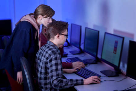 A group of people working as programmers discuss their work sitting in the office. The work of a programmer. Blue light.の写真素材