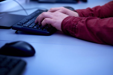 The hands of a man work on a keyboard on a personal computer in the office. Esports player.
