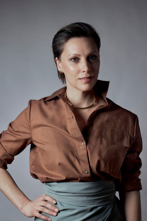 Portrait of a beautiful brunette woman with a fashionable hairstyle. He looks at the camera. Gray background.の写真素材
