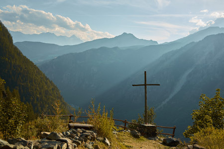 On a high hill stands a tall cross. High beautiful mountains. Yellow grass. The concept of faith.の写真素材