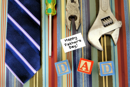 Collection of tools with tie and Fathers Day tag over a masculine patterned background