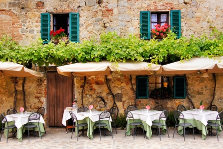 Cafe tables and chairs outside a quaint stone building in Tuscany, Italyの写真素材