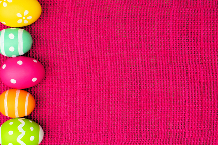 Colorful Easter egg side border over a pink burlap backgroundの写真素材