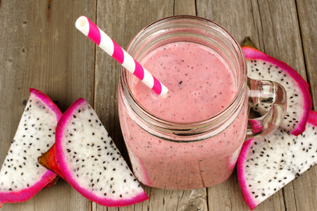 Pink raspberry dragon fruit smoothie in jar mug on a wood background downward viewの写真素材