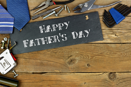 Happy Fathers Day written on slate with corner border of tools on old wood backgroundの写真素材