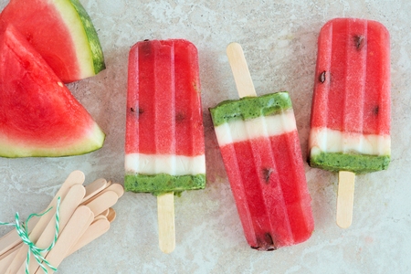 Watermelon popsicles with fresh melon slices on a white marble backgroundの写真素材