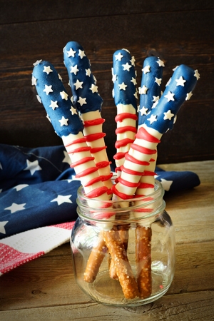 Fourth of July American flag themed pretzel rods in a mason jar against rustic woodの写真素材