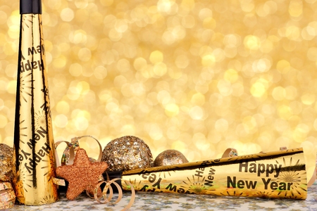 New Years Eve border of party noise makers and golden decor with twinkling light backgroundの写真素材
