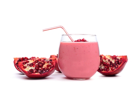 Pomegranate raspberry smoothie in a tumbler glass with pomegranate pieces isolated on whiteの写真素材