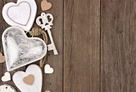 Side border of white and silver hearts and love themed decor on a rustic wooden backgroundの写真素材