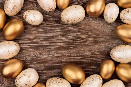 White and gold Easter egg frame against a rustic wood backgroundの写真素材