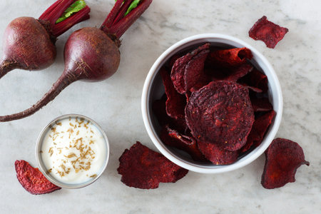 Bowl of healthy beet chips above view over a white marble backgroundの写真素材
