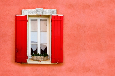 Red shuttered window against red ocher colored wallの写真素材