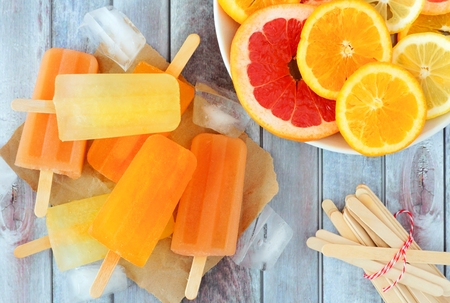 Orange, lemon and grapefruit ice pops, overhead scene on a rustic wood backgroundの写真素材