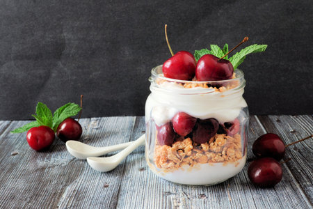 Delicious cherry parfait in a mason jar, scene on dark rustic backgroundの写真素材
